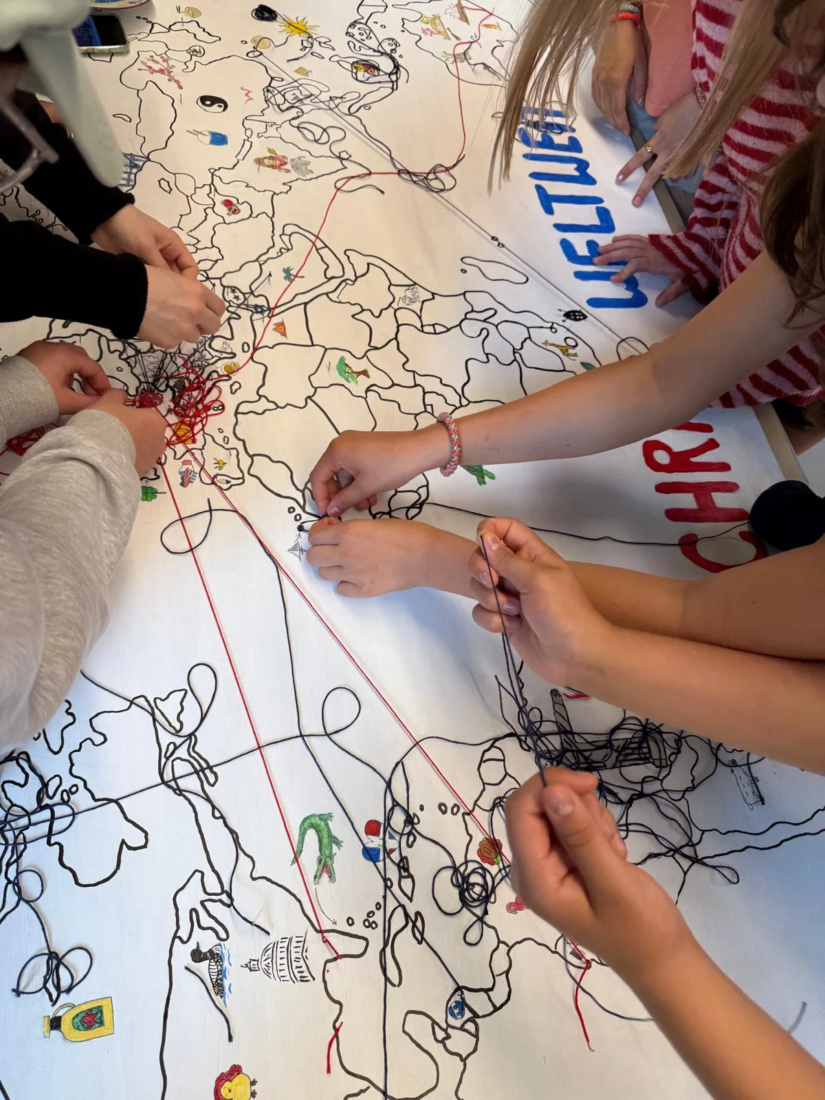 Schüler arbeiten an einer kreativen Landkarte, die Geschichten und Verbindungen weltweit darstellt.
