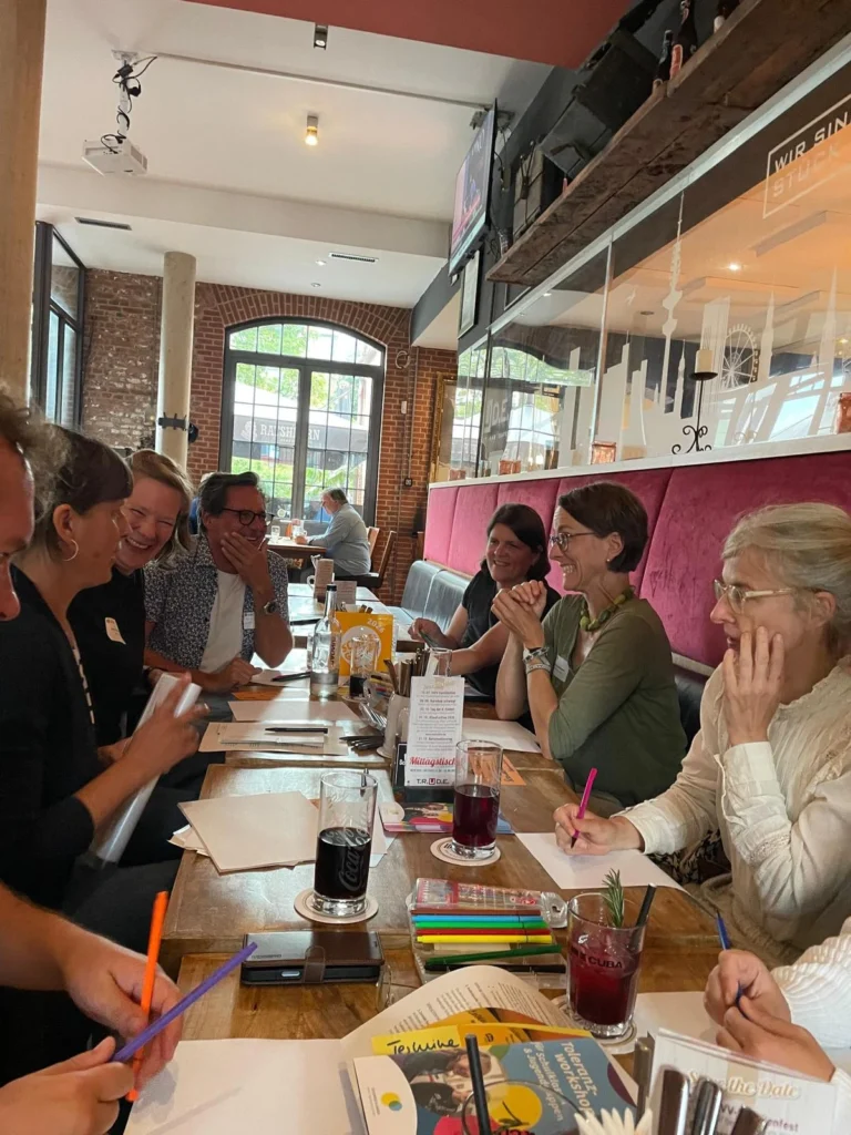 Gruppendiskussion in einem Café über Vielfalt mit Notizen und Getränken auf dem Tisch.