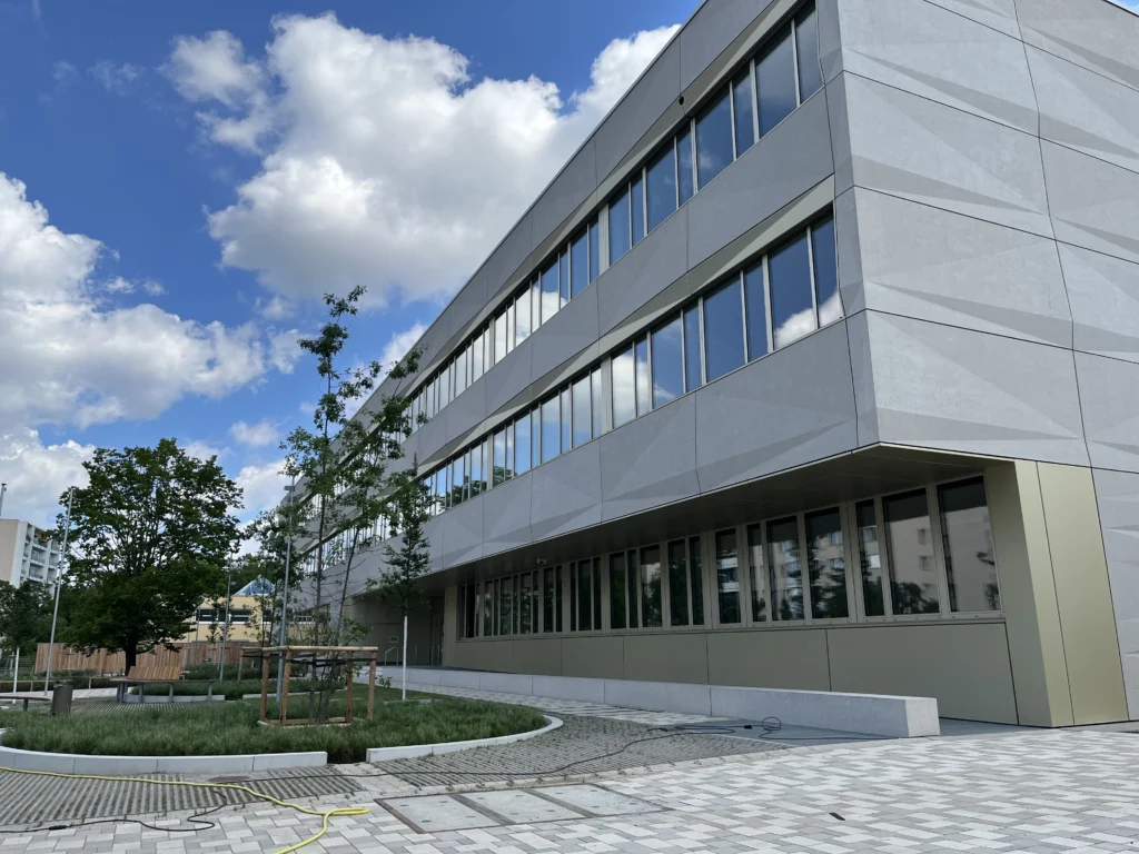 Moderne Architektur der Anna-Freud-Schule in Berlin mit grünen Flächen und blauem Himmel.