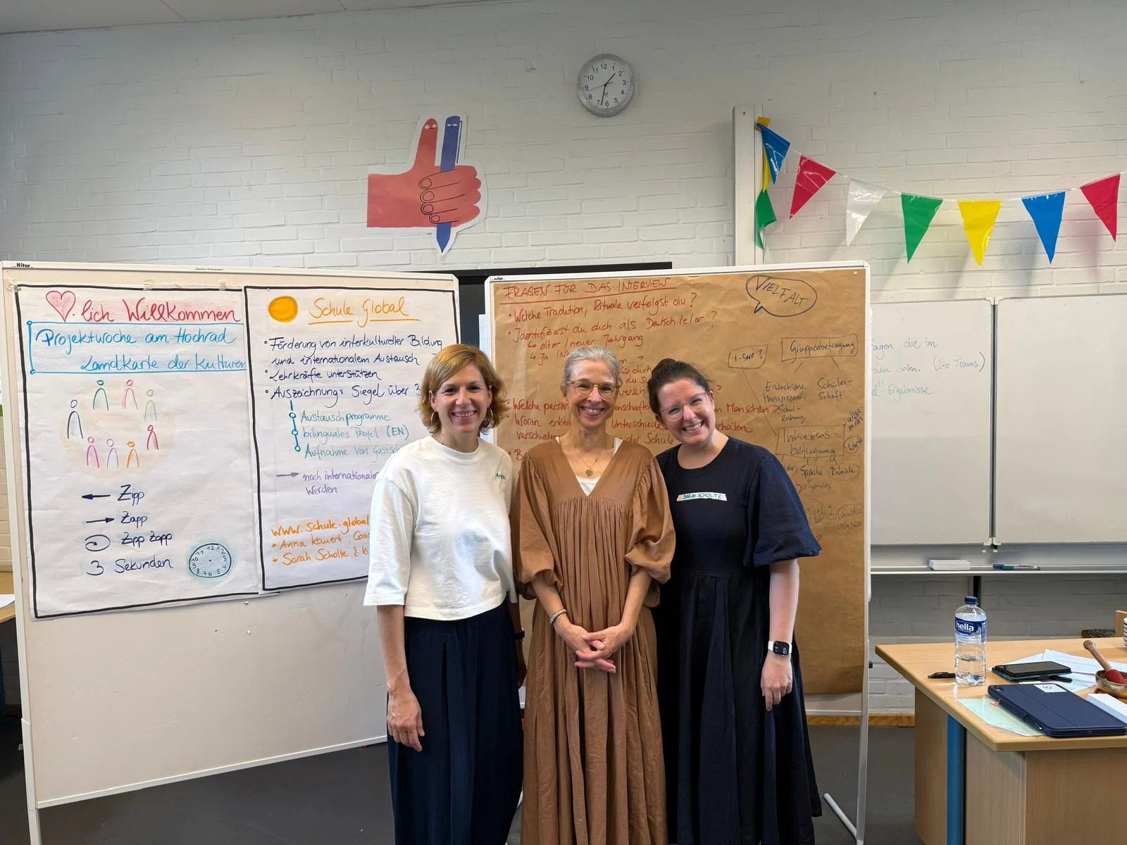 Drei Frauen stehen vor Flipcharts in einem Klassenzimmer während der Projektwoche "Schule Global am Hochrad".